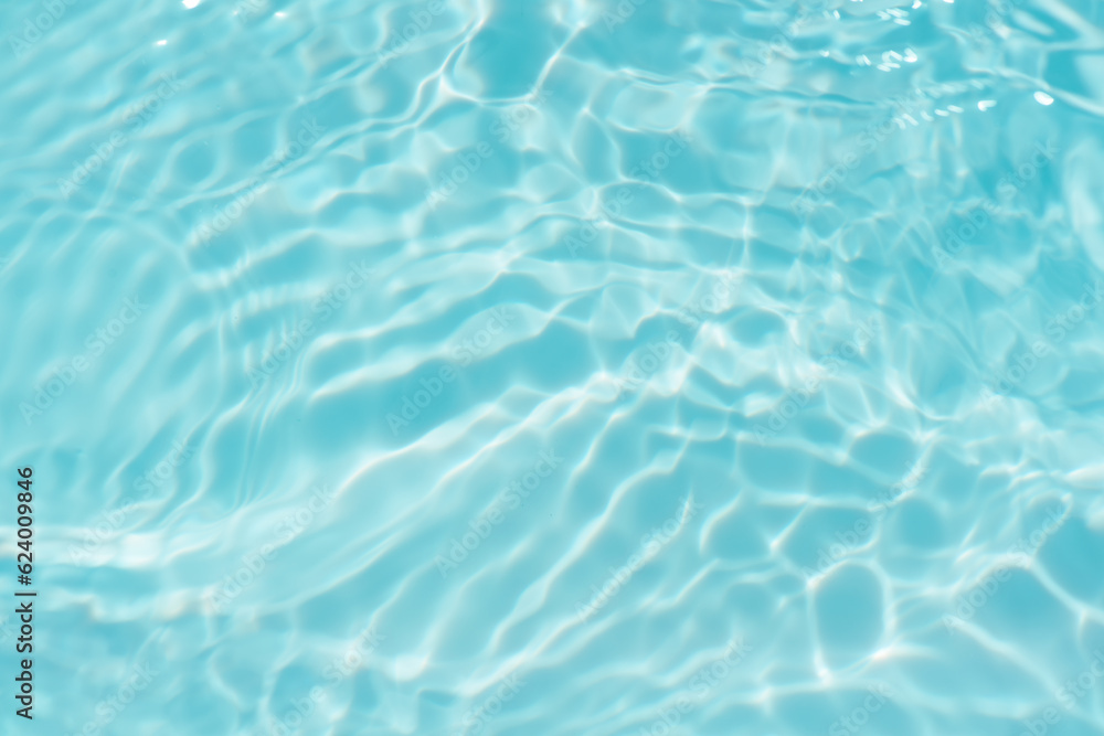 Blue water with ripples on the surface. Defocus blurred transparent blue colored clear calm water surface texture with splashes and bubbles. Water waves with shining pattern texture background.