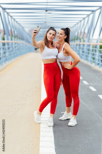 Two female friends taking selfies after a workout © Miguel Lifestyle