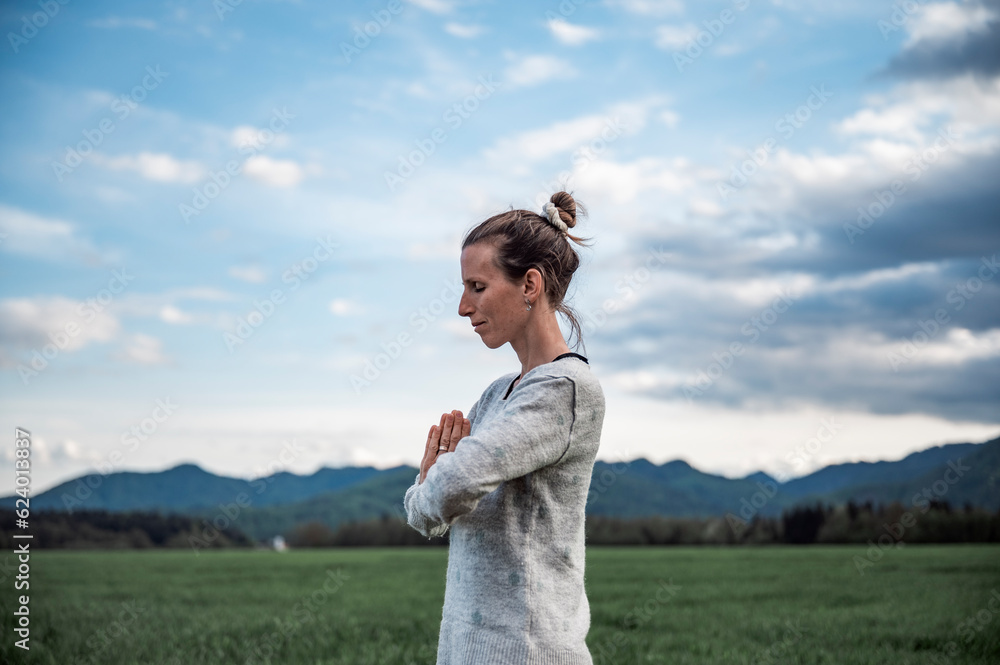 Profile view of a peaceful young woman meditating with her palms joined together in front of her chest Profile view of a peaceful young woman meditating with her palms joined together in front of her chest