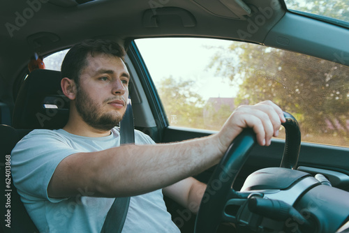 a young man driving a car.a rented car.a driving school.a taxi driver.a confident man in a auto.inside a car.Traveling by car.Brutal man.Renting a auto.Happy young man sitting in the auto.serious guy