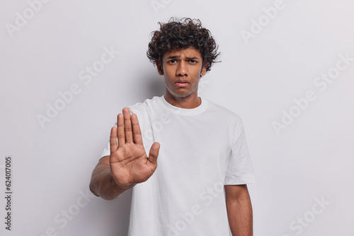 People negative emotions concept. Studio waist up of young upset Hindu standing in centre isolated on white background making and showing stop gesture not wanting doing or seeing something unpleasnt
