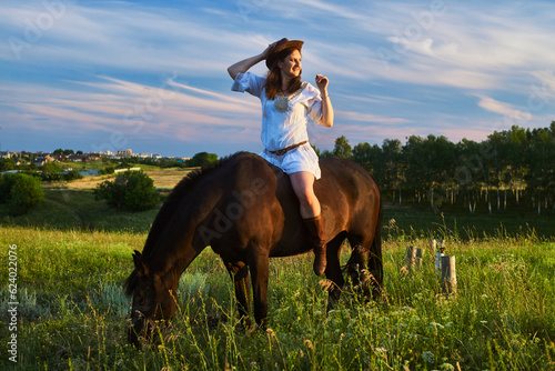 Beautiful girl sitting on a horse on the sunset © Andrey Tertichniy