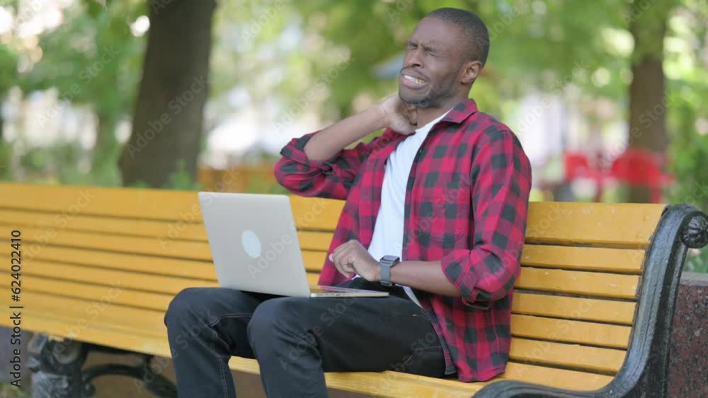Young African Man with Neck Pain Working on Laptop Outdoor Young African Man with Neck Pain Working on Laptop Outdoor