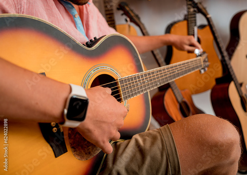 Young musician tuning a classical guitar in a guitar shop