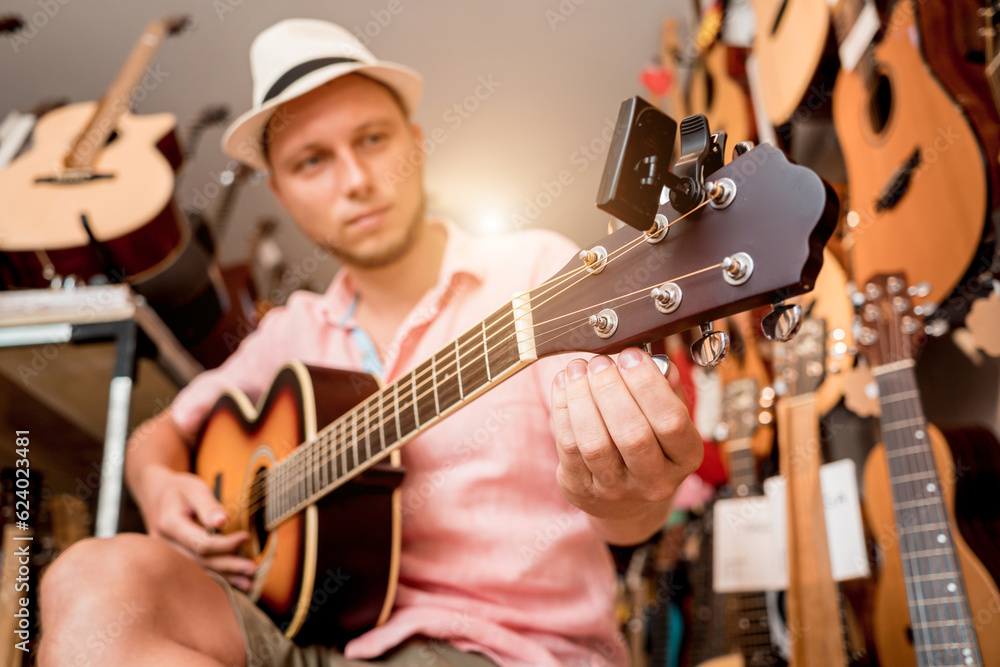 Obraz premium Young musician tuning a classical guitar in a guitar shop