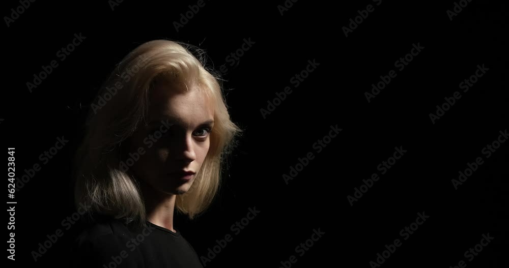 A contemplative Caucasian woman as she stands against a captivating black background. With a focused gaze directed towards the camera, she exudes a sense of depth and introspection. A contemplative Caucasian woman as she stands against a captivating black background. With a focused gaze directed towards the camera, she exudes a sense of depth and introspection.