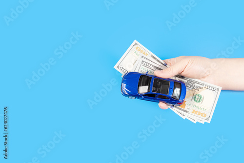 car and money cash in hand on a blue background, copy space