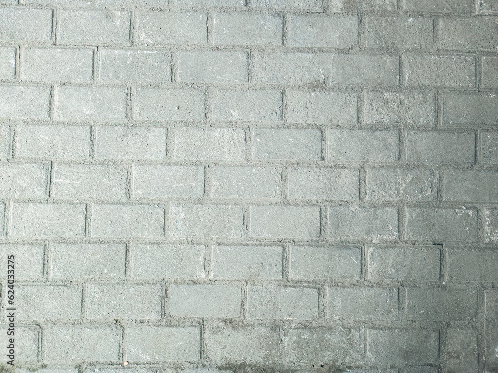 Fototapeta premium Textured gray brick wall background. Concrete wall for modern design use. Solid stone wall texture for projects. Industrial brick wall for architectural themes. Weathered brick wall close-up shot