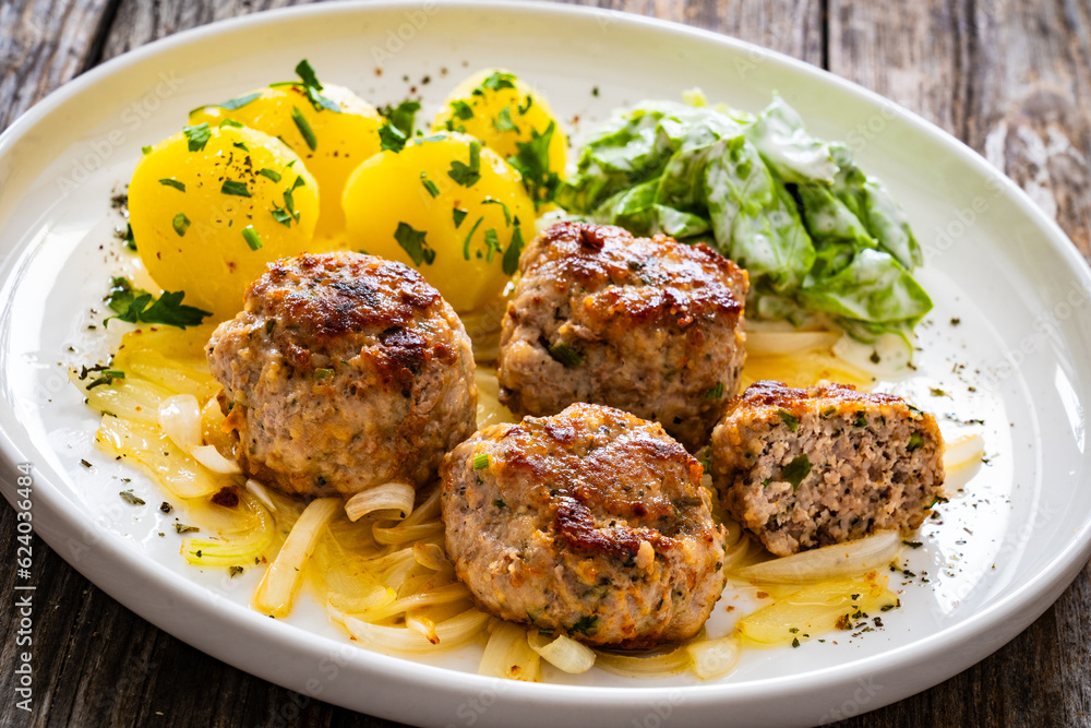 Seared pork meatballs with fried onion, boiled potatoes and lettuce in cream sauce on wooden table
Seared pork meatballs with fried onion, boiled potatoes and lettuce in cream sauce on wooden table