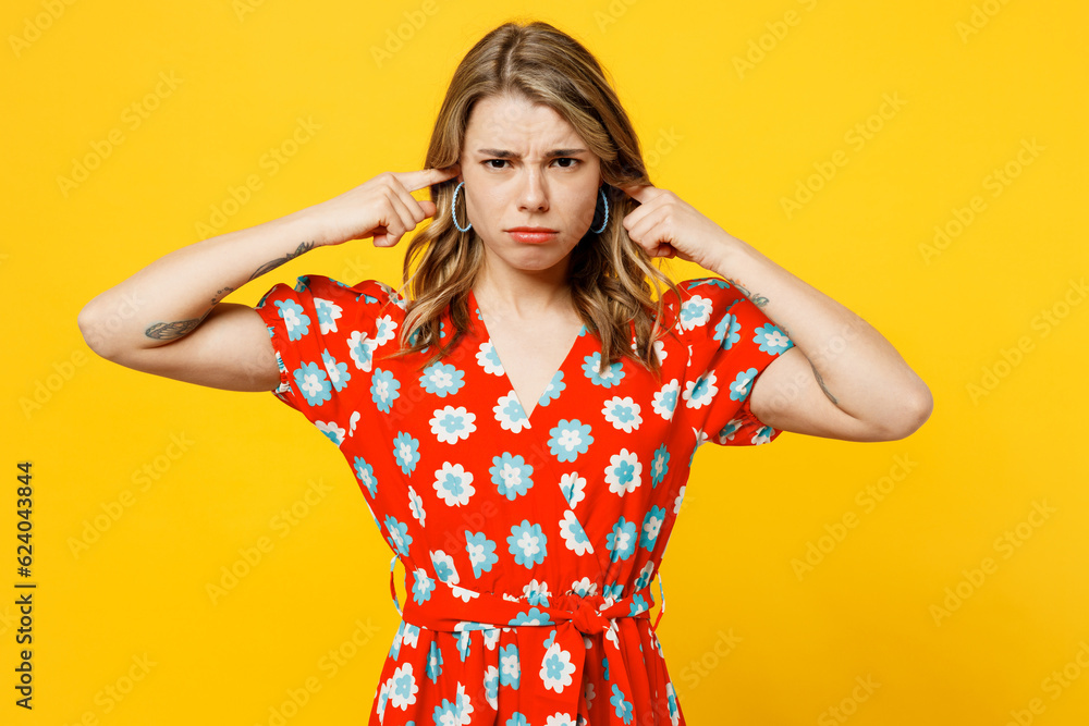 Young sad caucasian woman wear red dress casual clothes cover ears with hands fingers do not want to listen scream look camera isolated on plain yellow background studio portrait. Lifestyle concept. Young sad caucasian woman wear red dress casual clothes cover ears with hands fingers do not want to listen scream look camera isolated on plain yellow background studio portrait. Lifestyle concept.