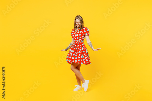 Full body side profile view young cheerful smiling satisfied fun caucasian woman she wear casual clothes spinning in red dress isolated on plain yellow background studio portrait. Lifestyle concept