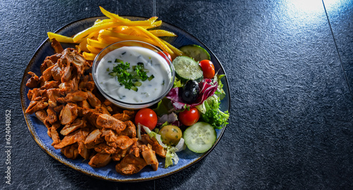 Kebab served with french fries, vegetable salad and tzatziki