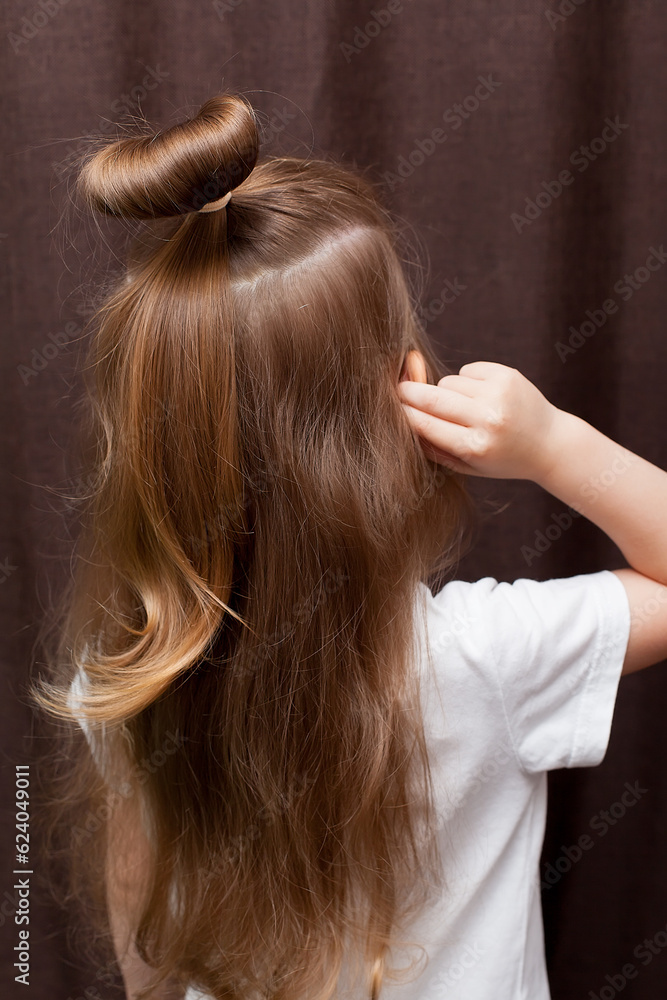 Fototapeta premium Rearview of little girl's head showing hair tied in bun.
