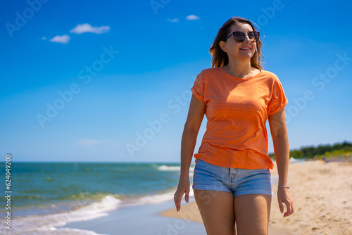 Beautiful woman walking on sunny beach

