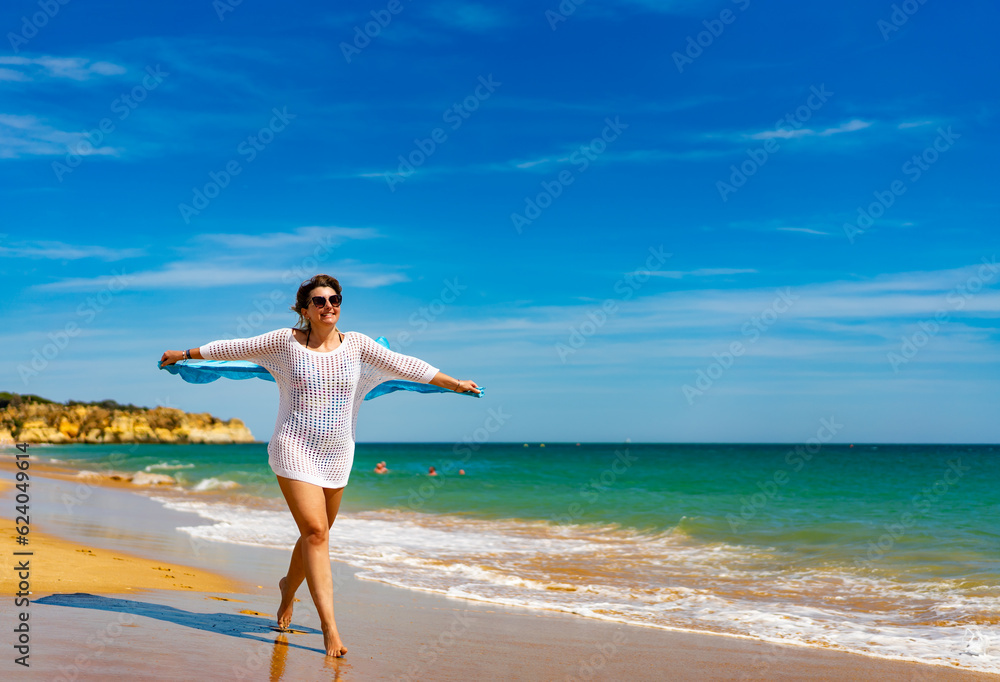 Beautiful woman walking on sunny beach holding shawl
Beautiful woman walking on sunny beach holding shawl