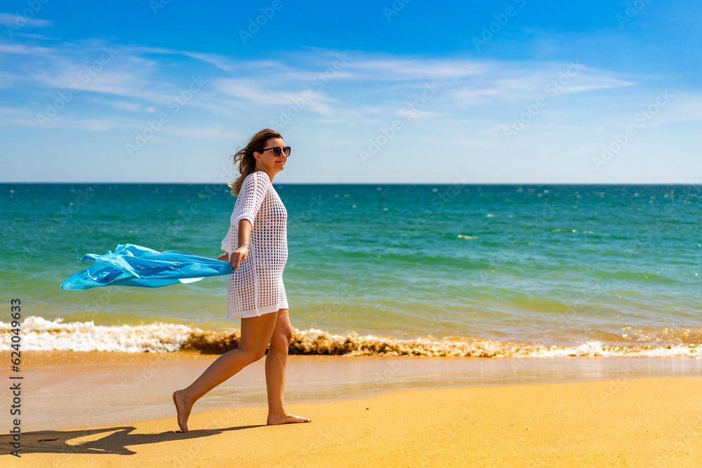 Beautiful woman walking on sunny beach holding shawl
Beautiful woman walking on sunny beach holding shawl