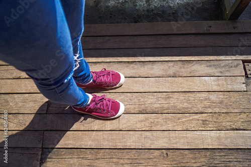 Blue jeans and red shoes on wood surface floor.
