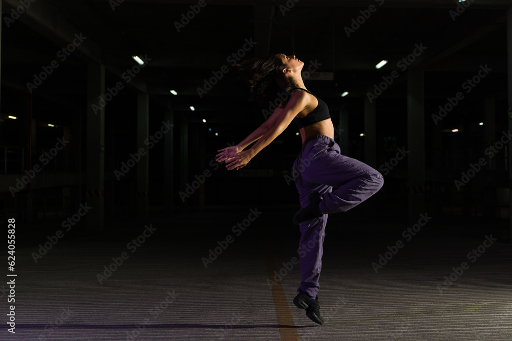 Profile of a happy female dancer dancing at night in the street