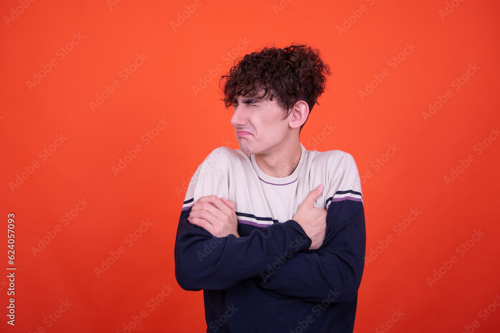 Young attractive emotional guy posing in the studio on an orange background. Young attractive emotional guy posing in the studio on an orange background.