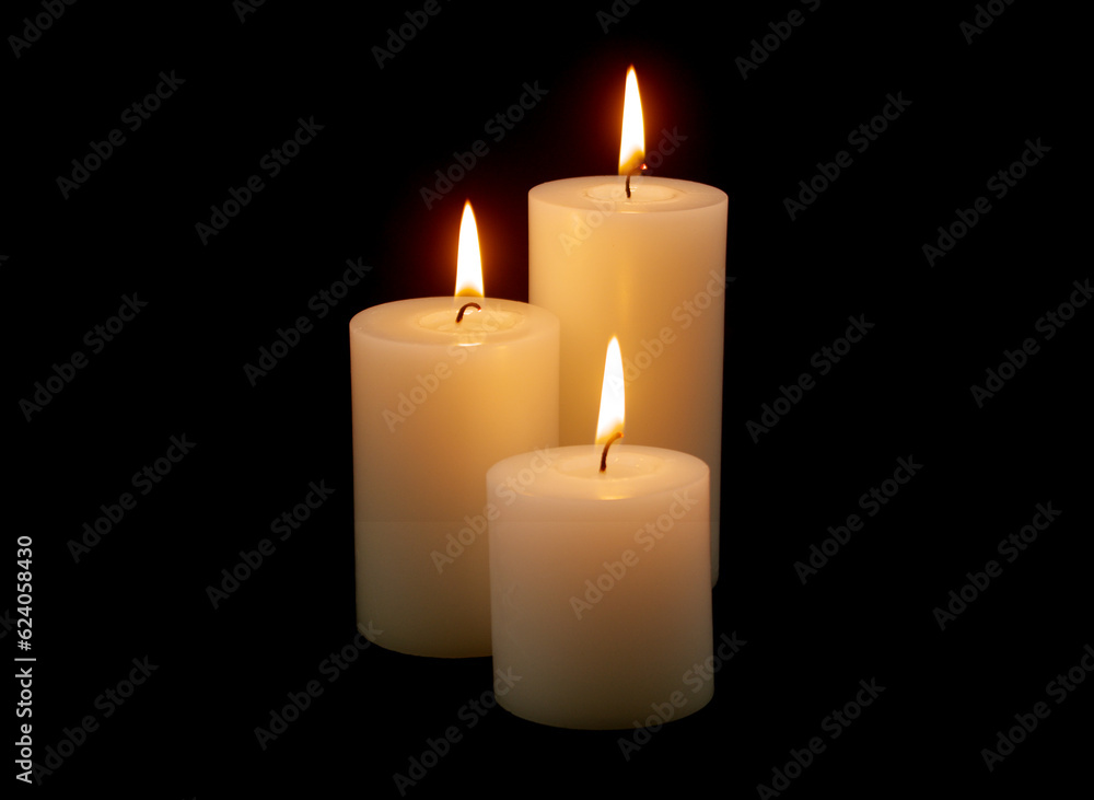 Three white candles with different size burning on black background. Three white candles with different size burning on black background.