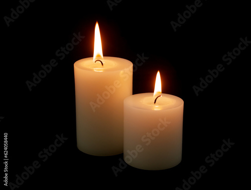 Two white candles burning on black background.
