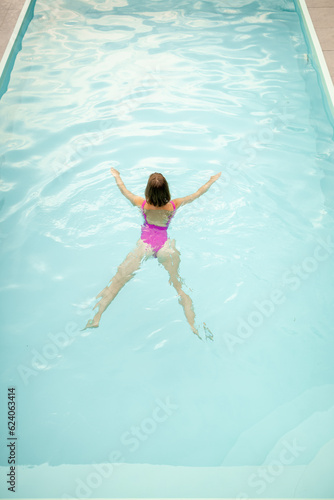 Woman swims at swimming pool, view from above