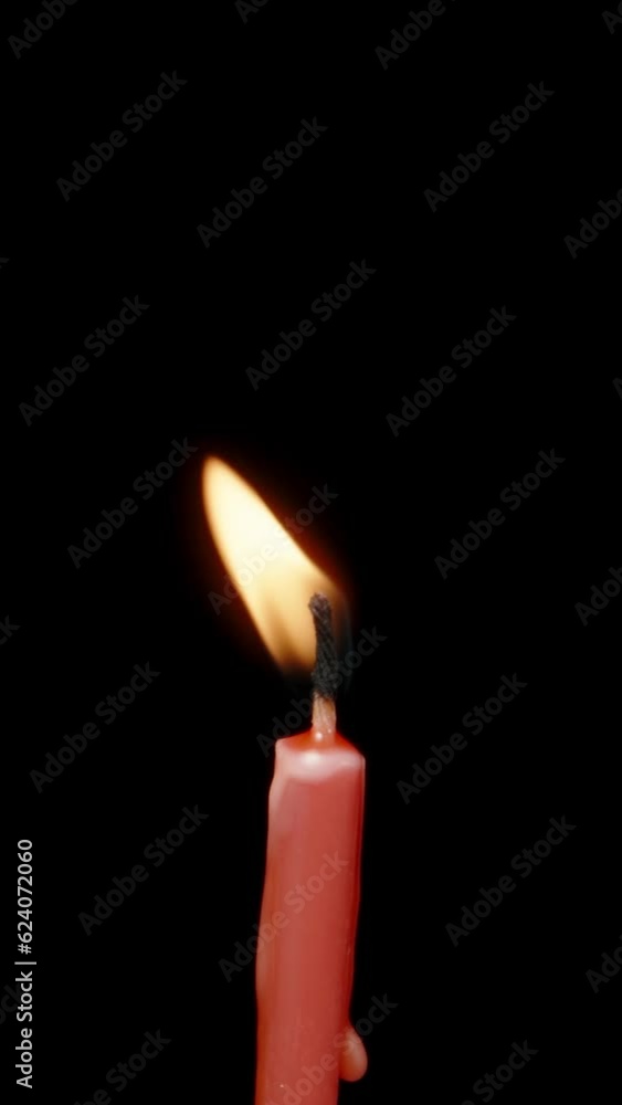A red candle on a black background rotates, blows the wind and blows it out. Vertical video. A red candle on a black background rotates, blows the wind and blows it out. Vertical video.