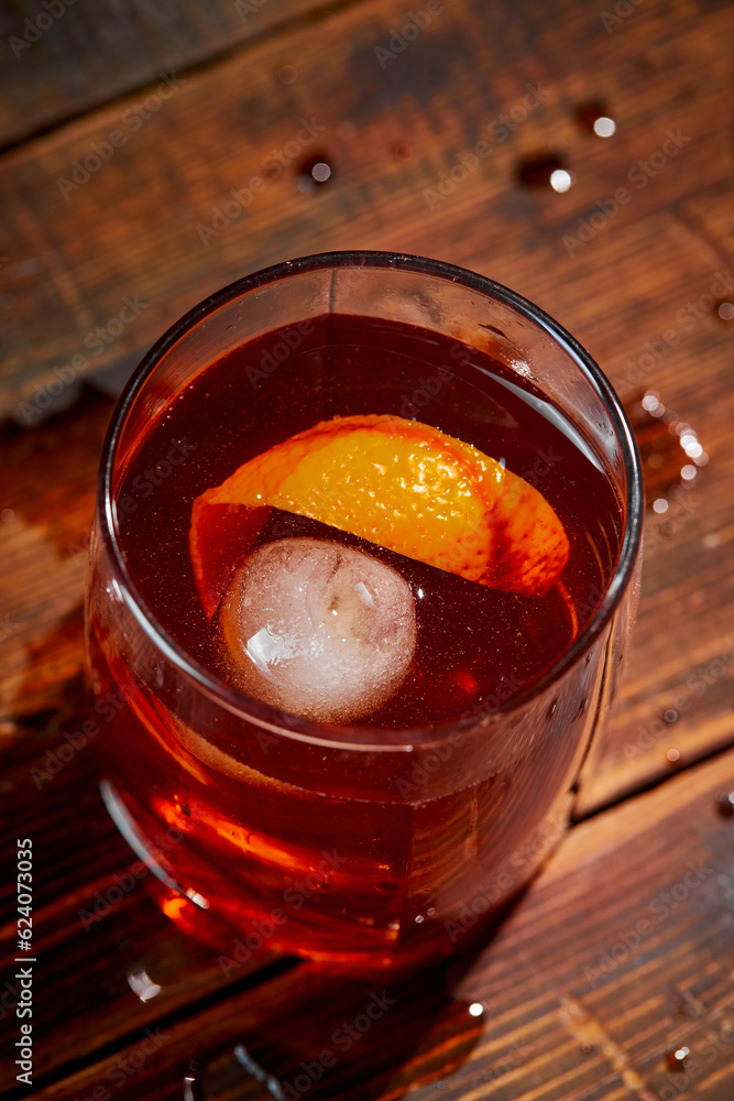 Alcoholic cocktail Negroni or non-alcoholic cocktail, drink with ice and orange peel as decoration on wooden table Alcoholic cocktail Negroni or non-alcoholic cocktail, drink with ice and orange peel as decoration on wooden table