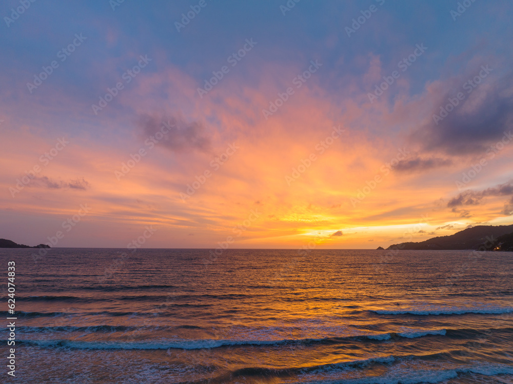 The golden light pierced the clouds reflecting the water over the sea of Patong Beach..reflection Sky texture background. .A mass of rain clouds float over the sea of Patong beach.