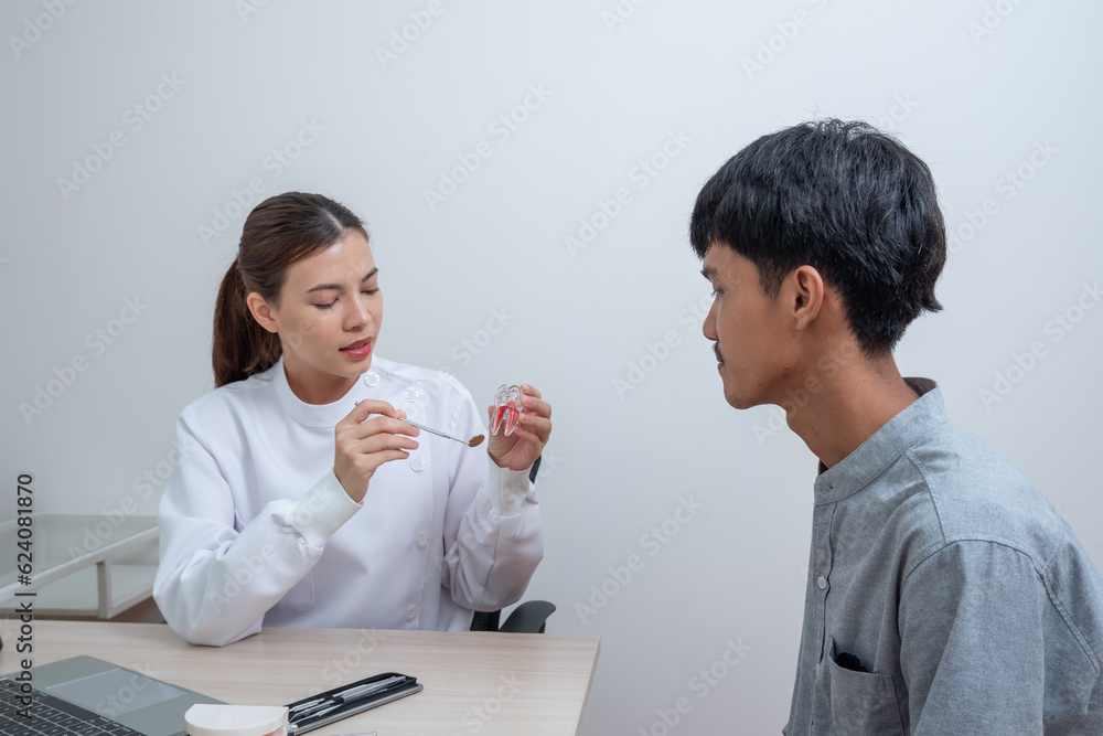 Beautiful young woman dentist in uniform holding dental prosthetic teeth showing red roots and explaining to patient. Beautiful young woman dentist in uniform holding dental prosthetic teeth showing red roots and explaining to patient.