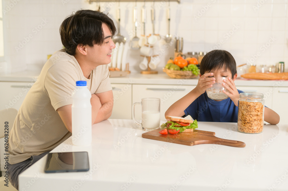 Happy Young Asian father and son eating healthy food in kitchen at home