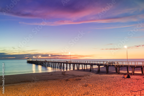 Henley Beach jetty at dusk with the tranquil sea embracing the weathered pillars with purple cluds above, South Australia photo