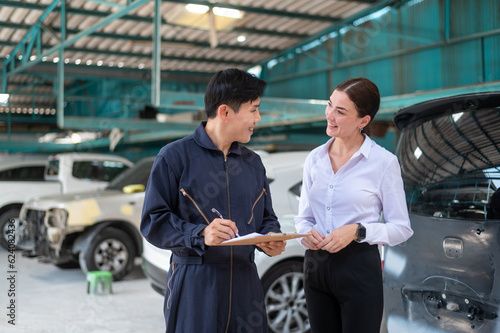 A young Caucasian woman explains about her car problems to mechanic man in auto repair shop