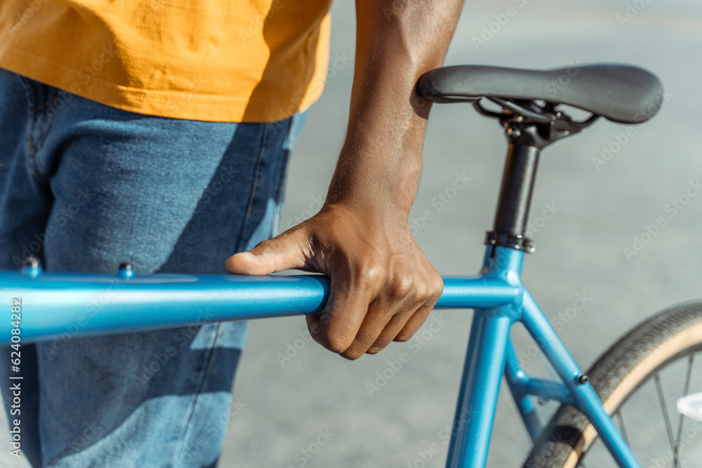 Closeup portrait of African American man holding bicycle on urban street selective focus on hand