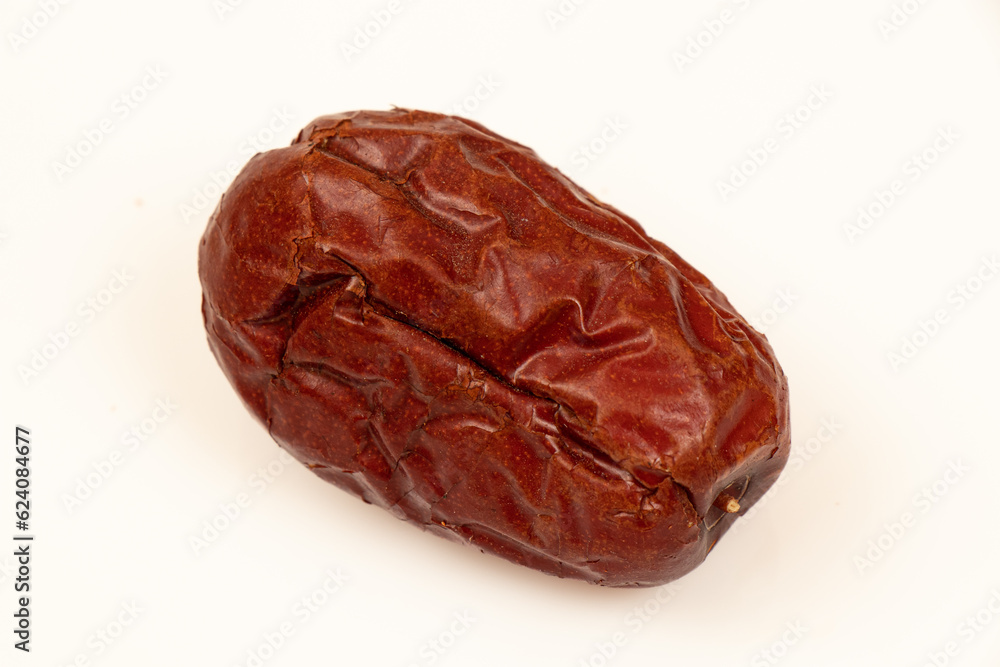 Dried jujube seeds which are brown overlay on a white background. Jujube seeds is an ingredient in desserts, soups and drinks. Close-up Dried jujube seeds which are brown overlay on a white background. Jujube seeds is an ingredient in desserts, soups and drinks. Close-up