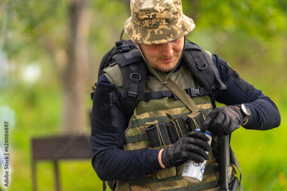 A man in military uniform opens a can of beer