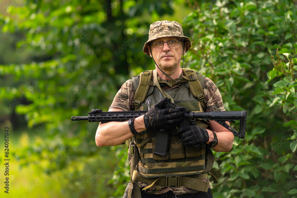 Portrait of a man with a weapon on a background of vegetation
