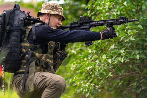 A man in military uniform aims a rifle