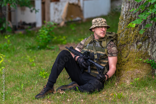 Obraz na płótnie A man in military uniform with a weapon, looks around w salonie