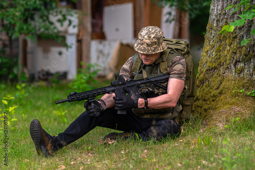 Obraz na płótnie A man in military uniform reloads a rifle w salonie