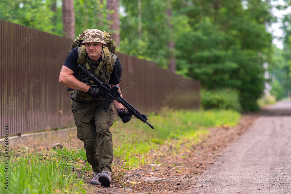 Armed man crouching along the fence