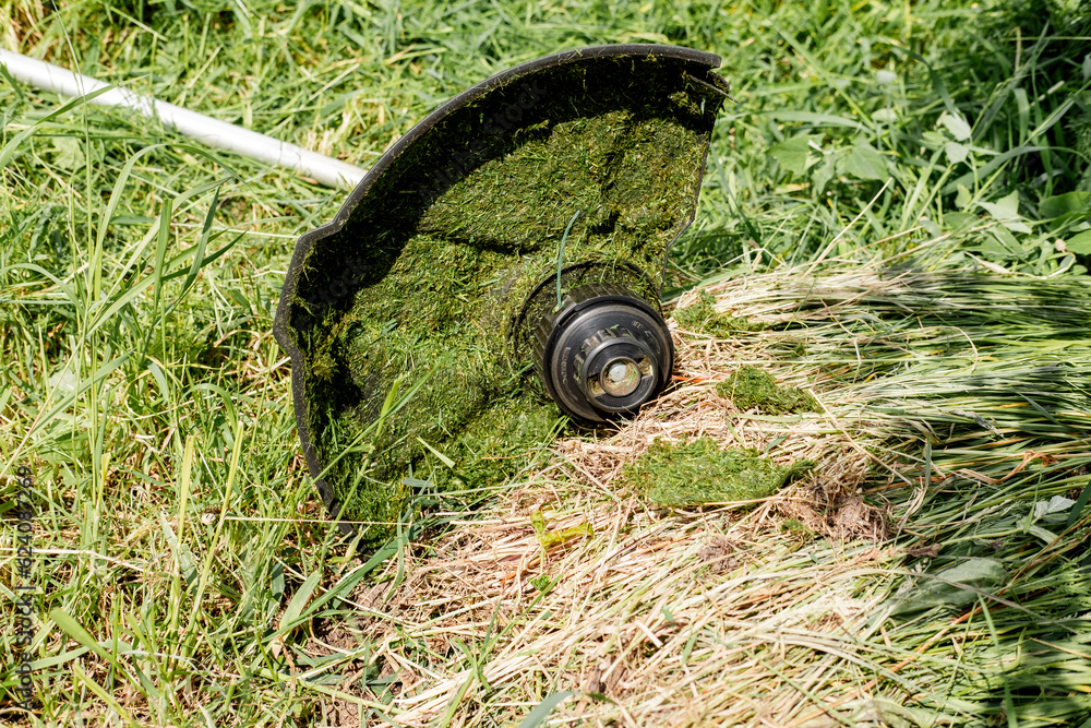 Fototapeta premium part of an electric lawn mower in the grass, closeup