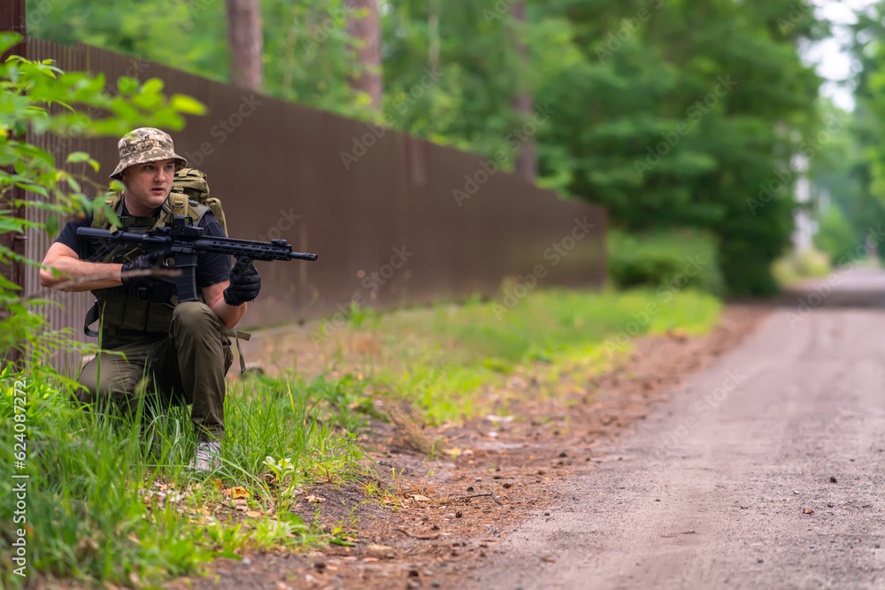 A warrior in a light, military uniform crouched on the side of the road