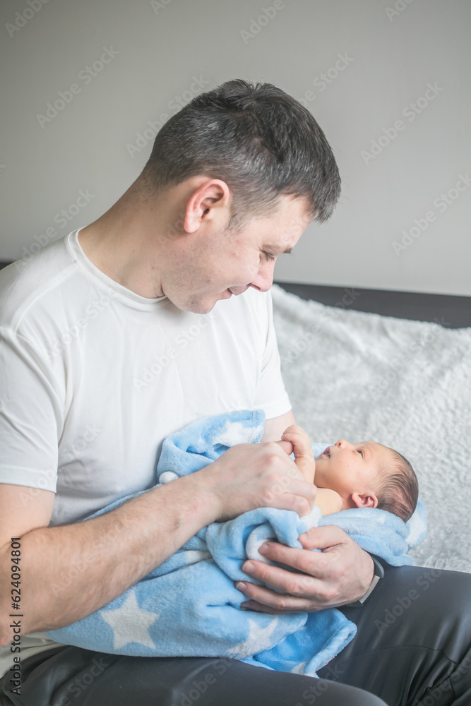 Father with his son, tiny infant. Newborn baby smiling, laughing and looking up at him. Daddy showing affection to baby. Father with his son, tiny infant. Newborn baby smiling, laughing and looking up at him. Daddy showing affection to baby.