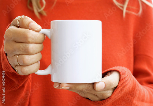 Vászonkép Girl is holding white 11 oz mug in hands with orange sweater