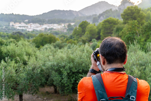 Man with backpack photographs a beautiful landscape at sunset