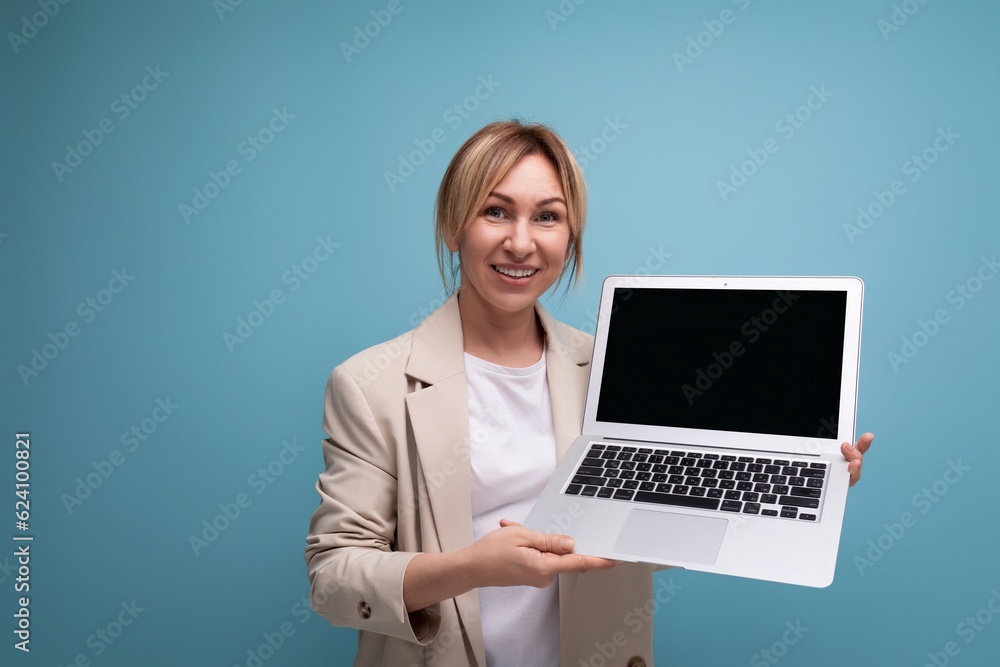successful fair-haired young business woman demonstrates the screen of an open laptop on the background of the studio successful fair-haired young business woman demonstrates the screen of an open laptop on the background of the studio