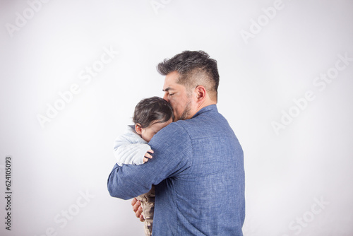 Beautiful photo of dad holding baby on light photo studio background. Family and baby concept. © artrolopzimages