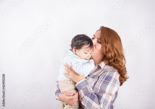 Beautiful photo of mom holding baby on light background in photo studio. Family and baby concept.