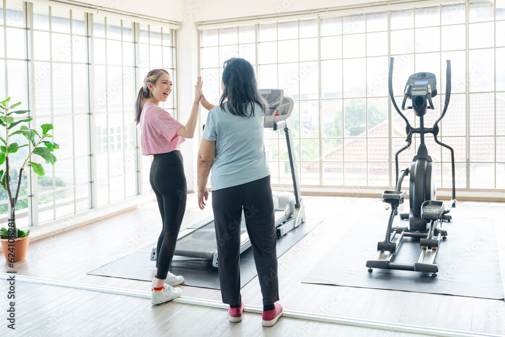 Fototapeta premium Asian young lady and old lady touching hand for motivation each others to workout at gym, concept healthy lady and life balance